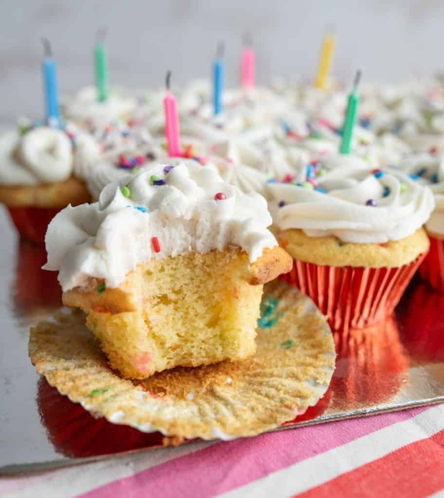 vanilla cupcakes with white icing and rainbow sprinkles for birthday cupcakes with a candle in each