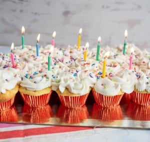 vanilla cupcakes with white icing and rainbow sprinkles for birthday cupcakes with a candle in each