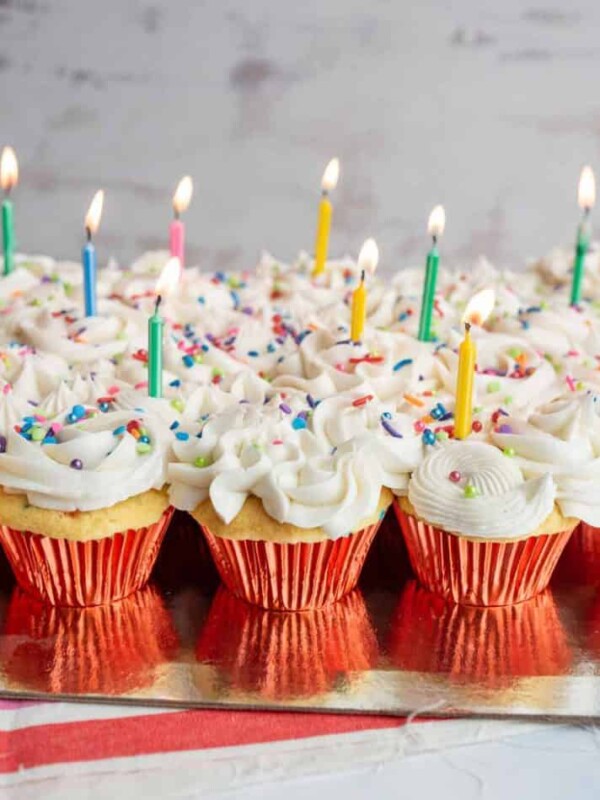 vanilla cupcakes with white icing and rainbow sprinkles for birthday cupcakes with a candle in each