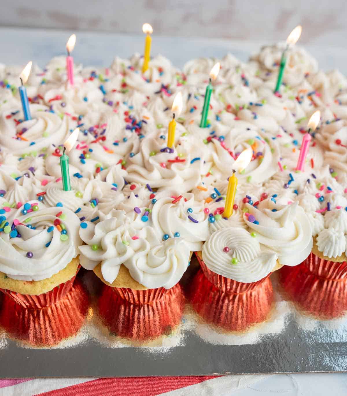 vanilla cupcakes with white icing and rainbow sprinkles for birthday cupcakes with a candle in each