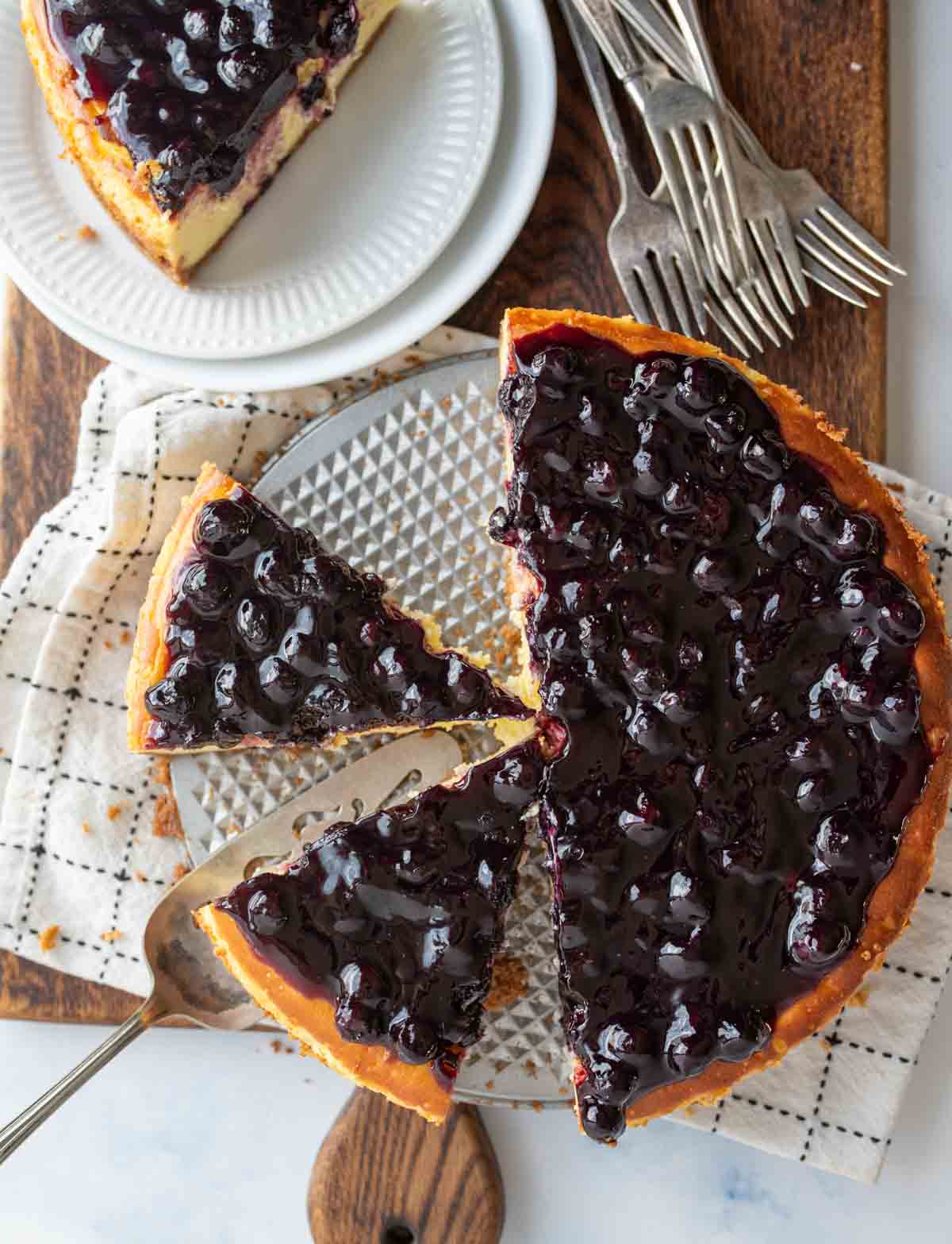 top view of a whole blueberry cheesecake with half cut into slices