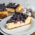 one slice portioned from a whole blueberry cheesecake