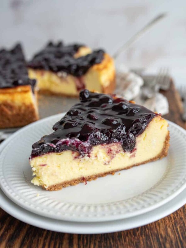 one slice portioned from a whole blueberry cheesecake