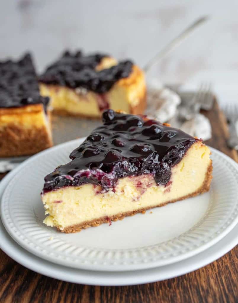 one slice portioned from a whole blueberry cheesecake