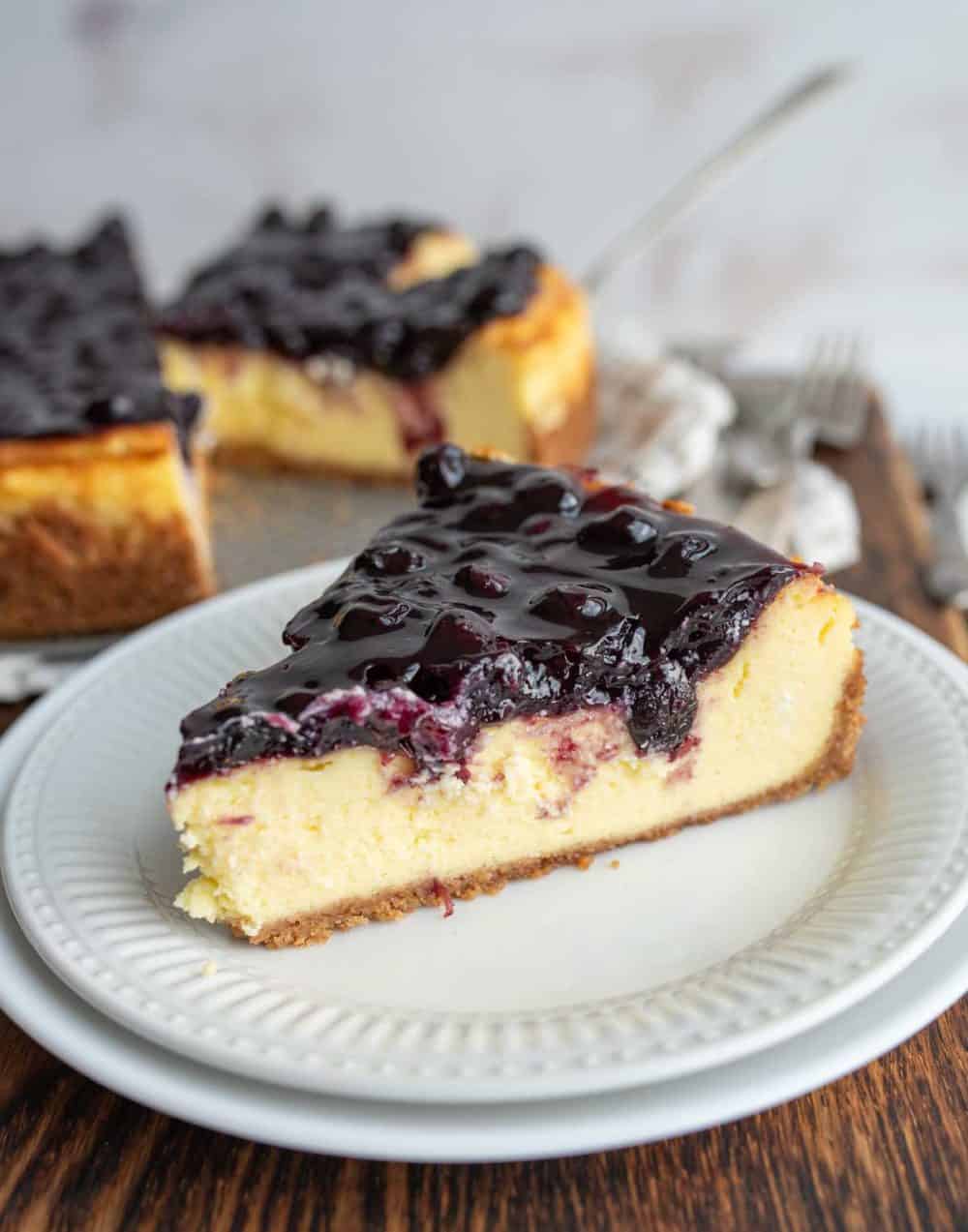 one slice portioned from a whole blueberry cheesecake