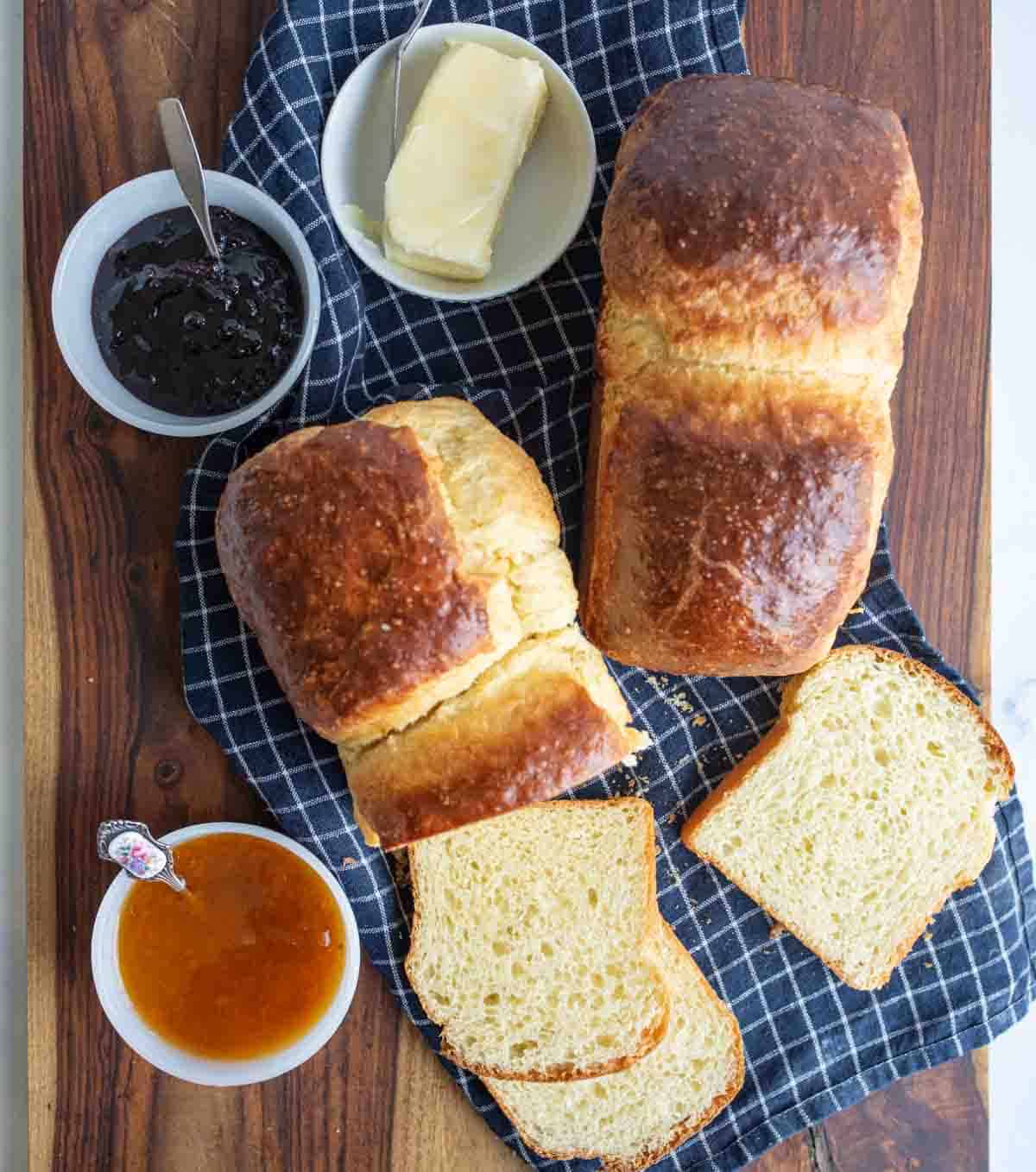 golden baked brioche bread loafs sliced with butter and jam on the side