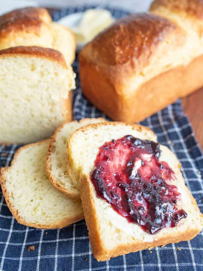 golden baked brioche bread loafs sliced with butter and jam