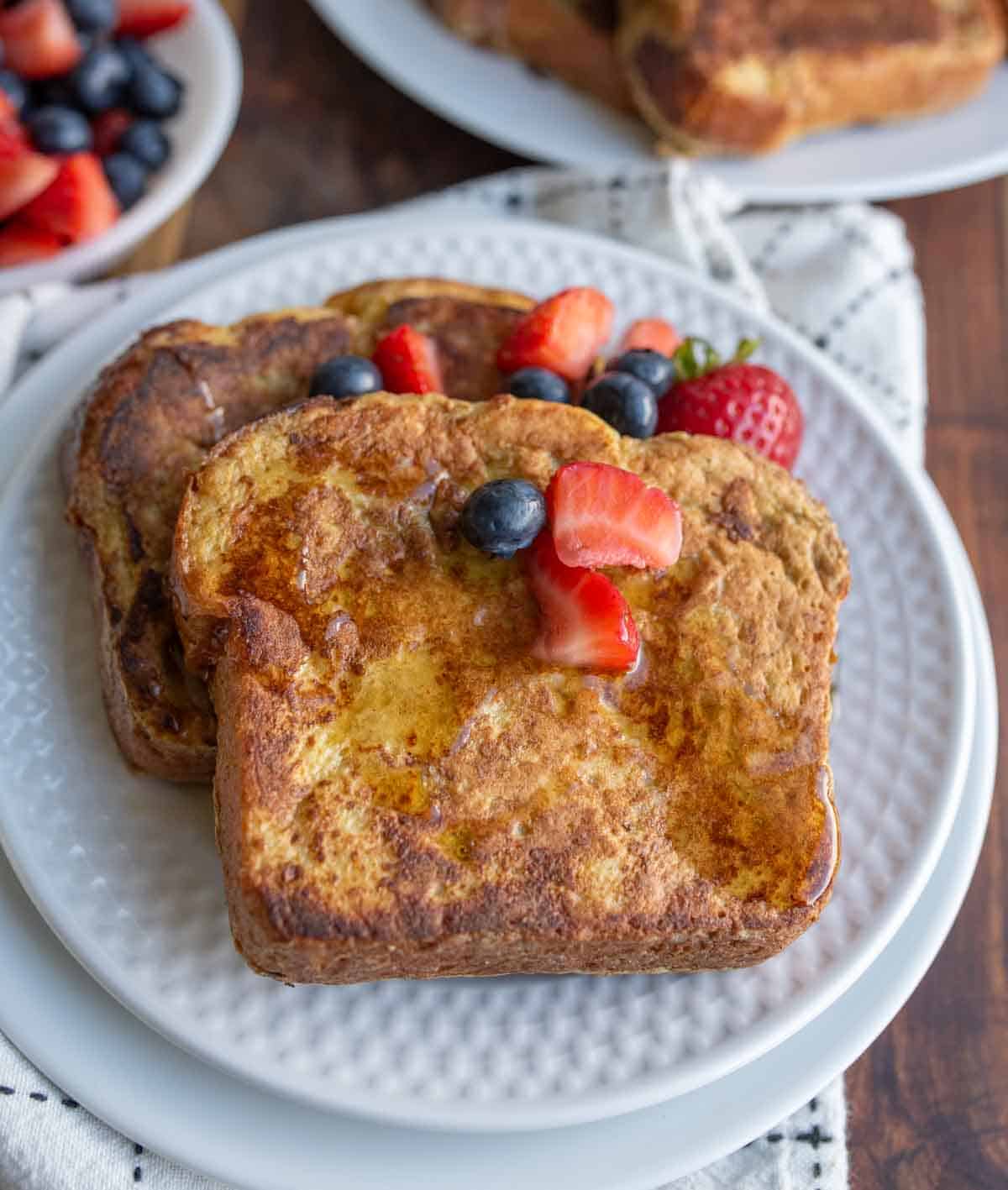 syrup over thick sliced brioche french toast with berries on top