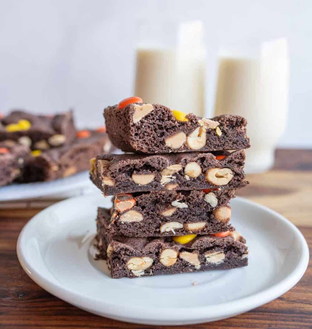 Stack of cake bars with glasses of milk in the background. 