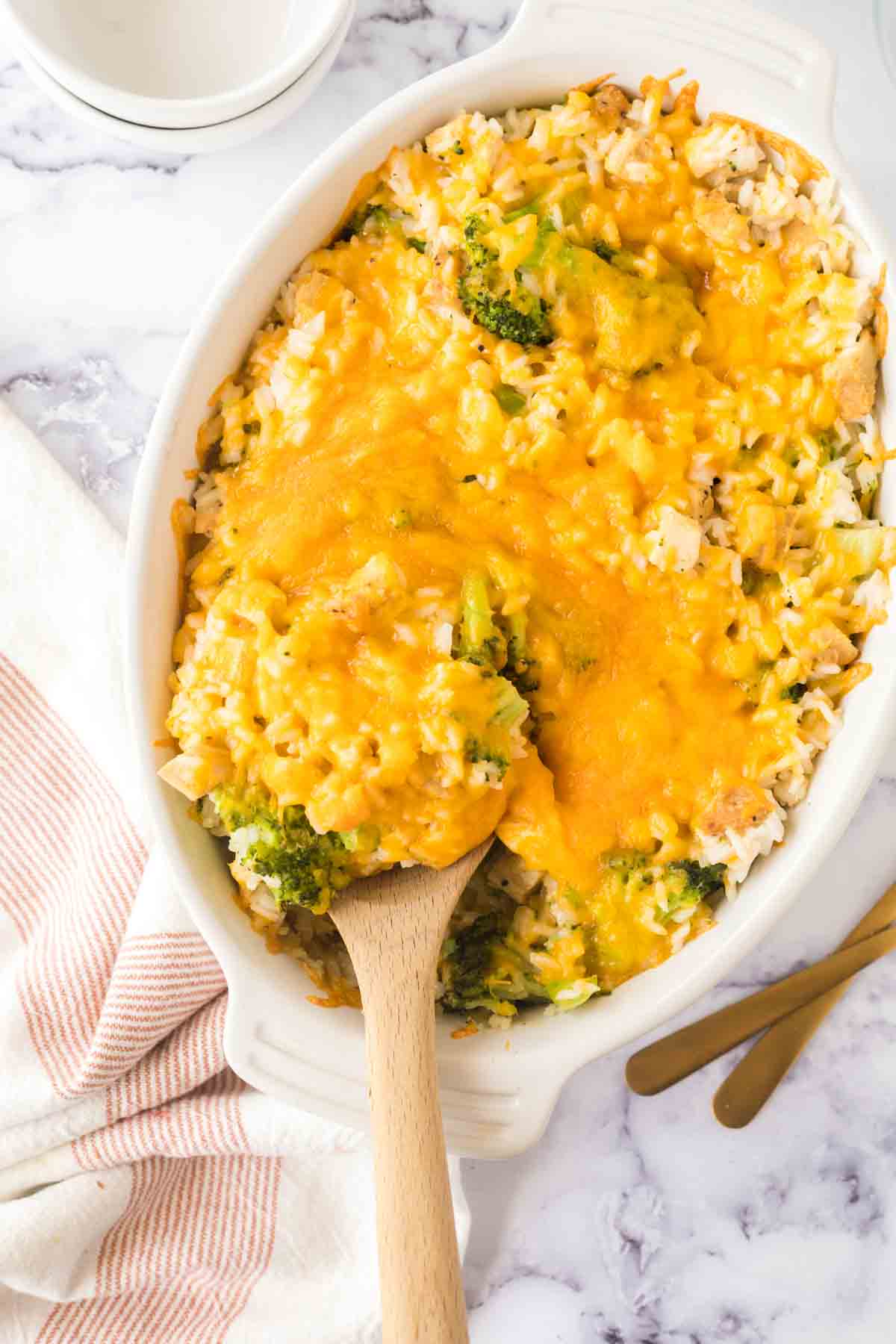 top view of wooden spoon scooping chicken broccoli rice casserole from the baking dish