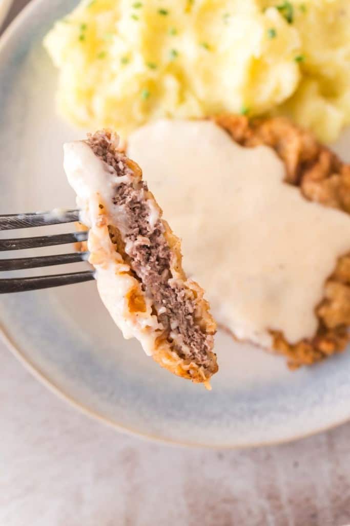 close up of a bite of chicken fried steak on a fork POV