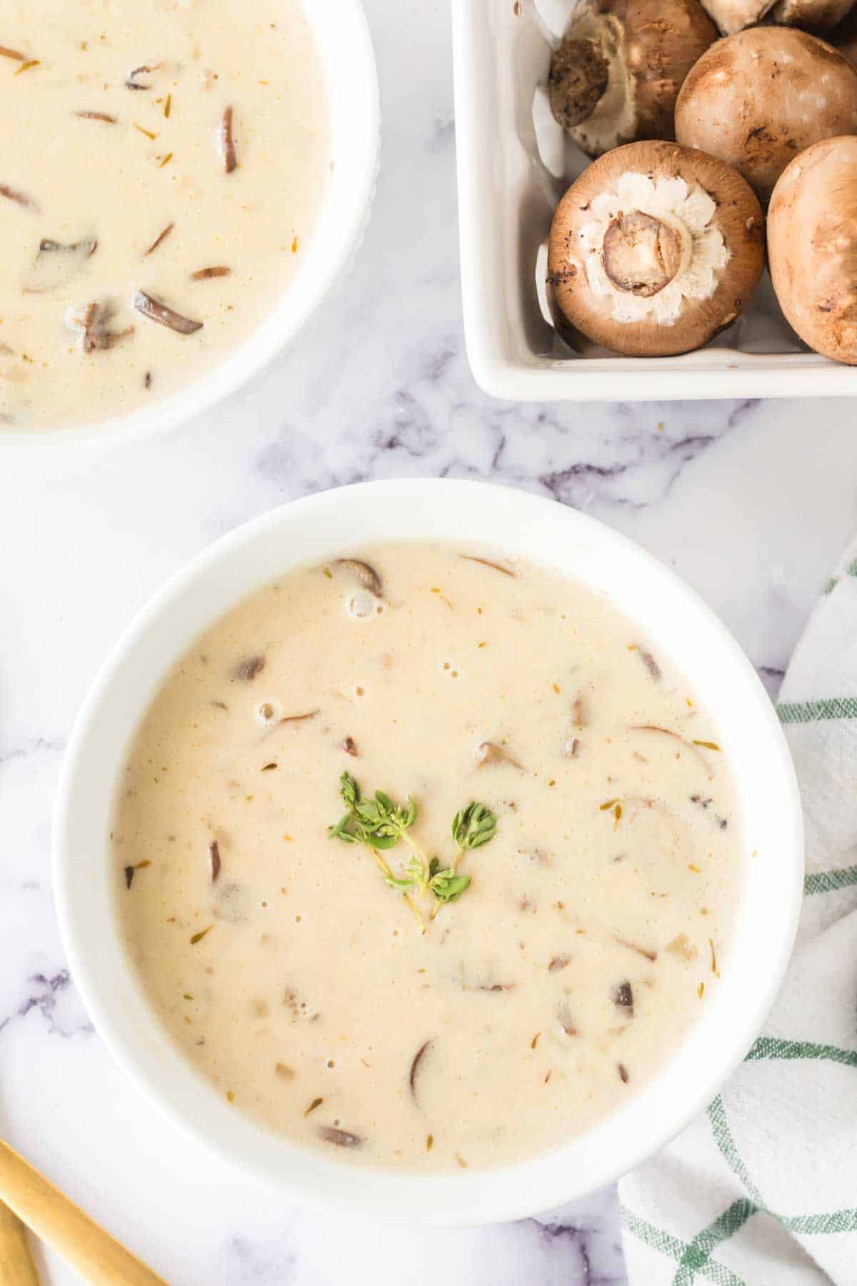 top view of a white bowl of cream of mushroom soup with spoons