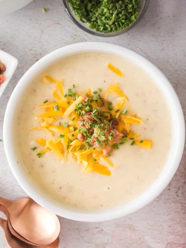 top view of a bowl of cream of potato soup with cheese bacon and chives on top