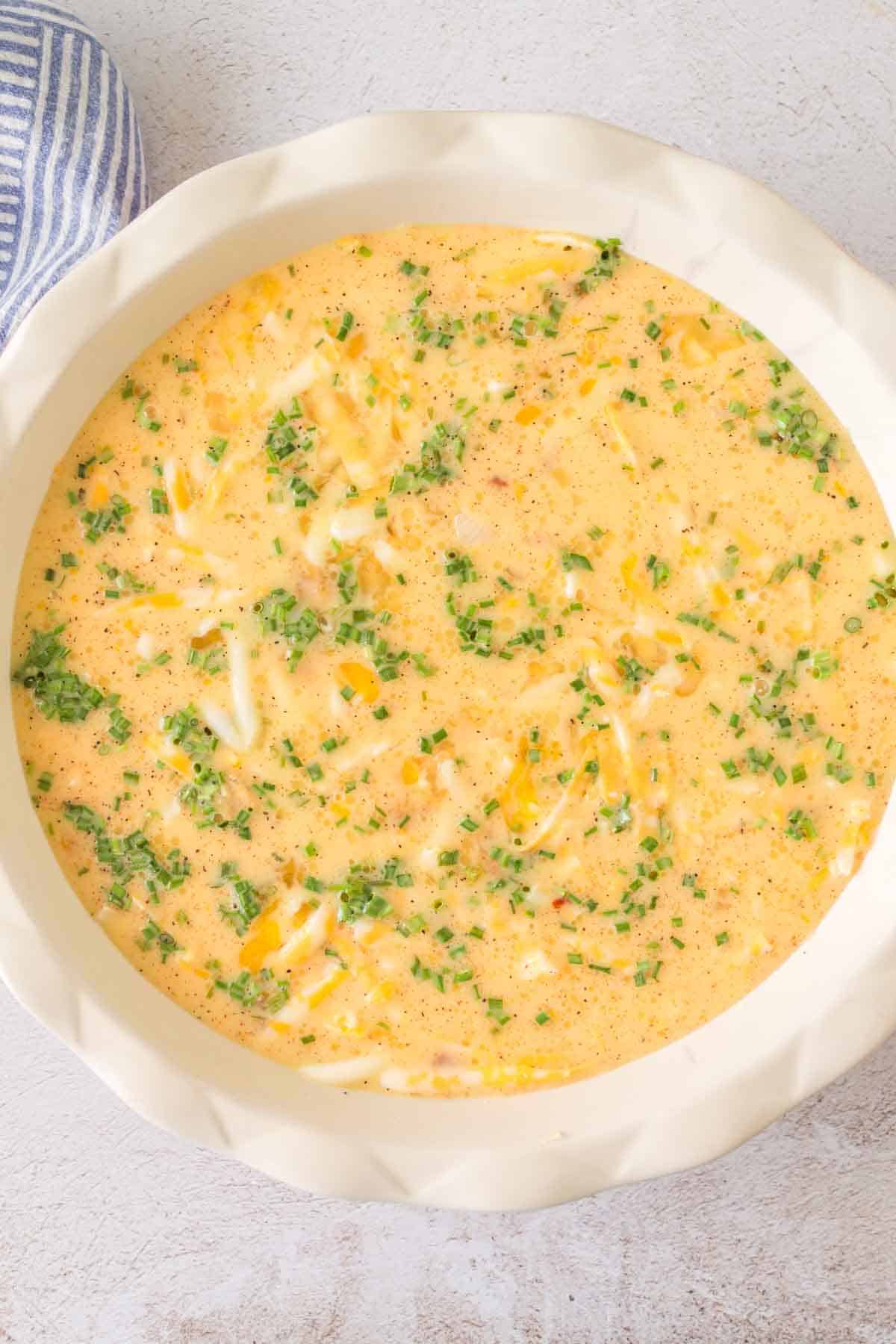 top view of a whole crustless quiche in the baking dish uncooked