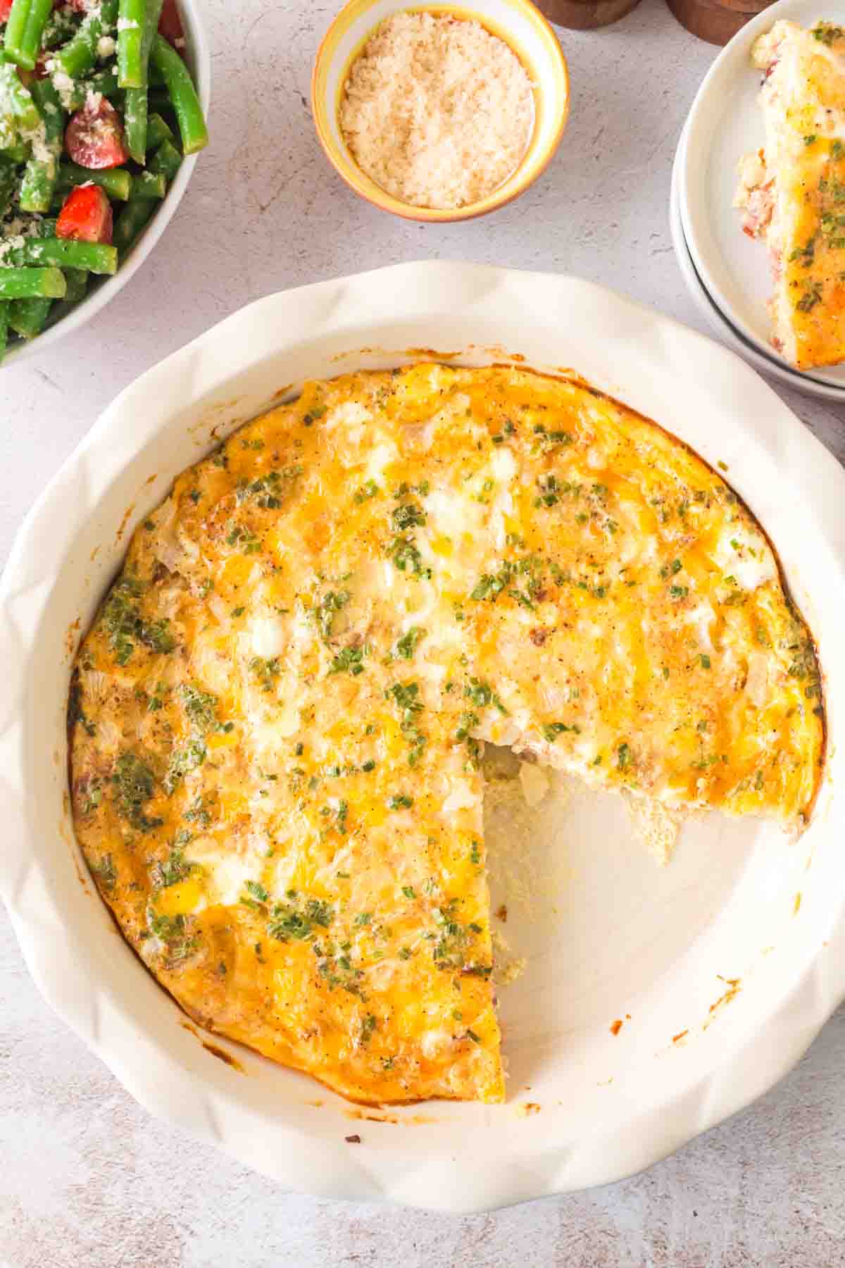 top view of a whole crustless quiche in the baking dish with one slice taken out