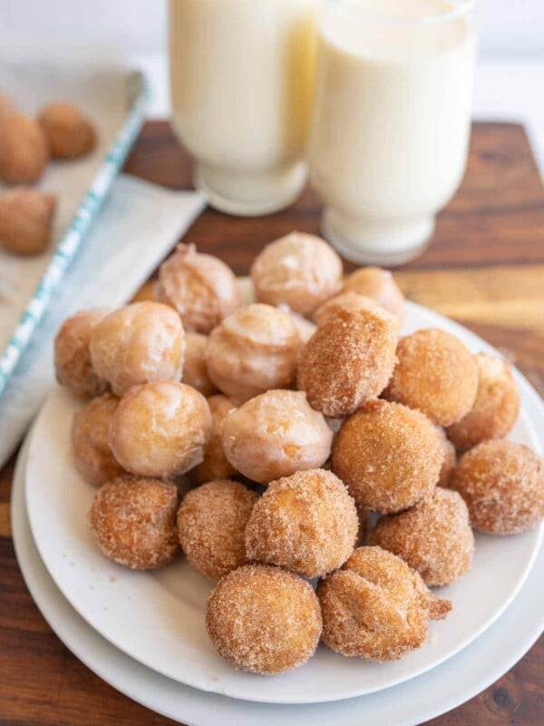 plate stacked with round iced and sugar donut hole bites
