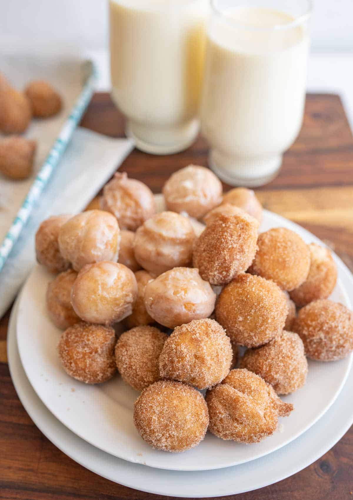 plate stacked with round iced and sugar donut hole bites