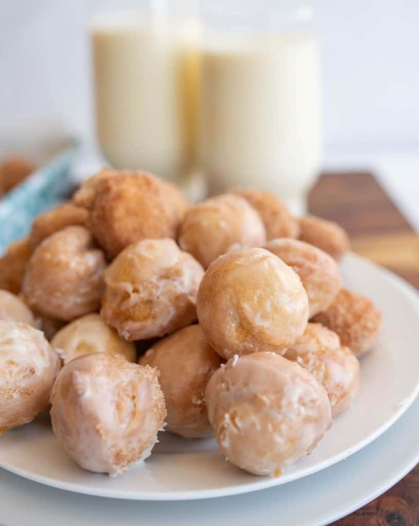 plate stacked with round iced and sugar donut hole bites