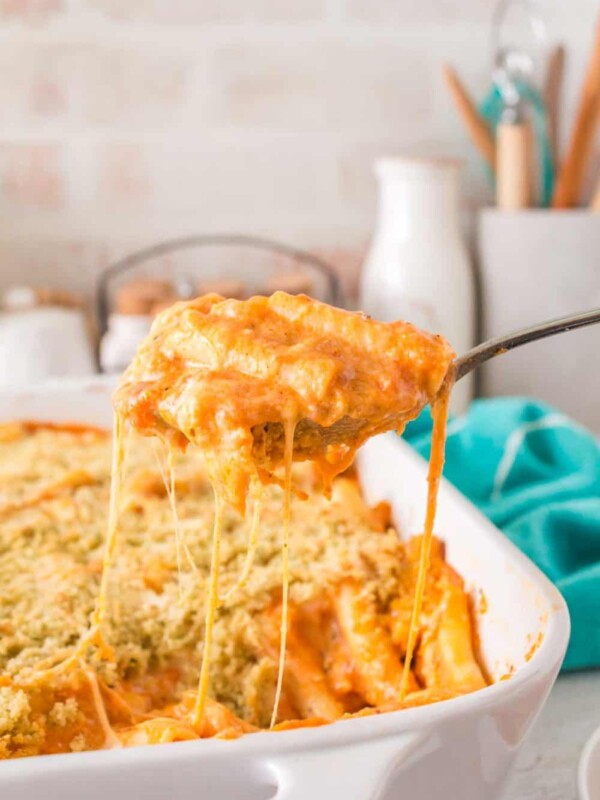five cheese zita forno pasta with a creamy red sauce in a white baking dish being spooned out