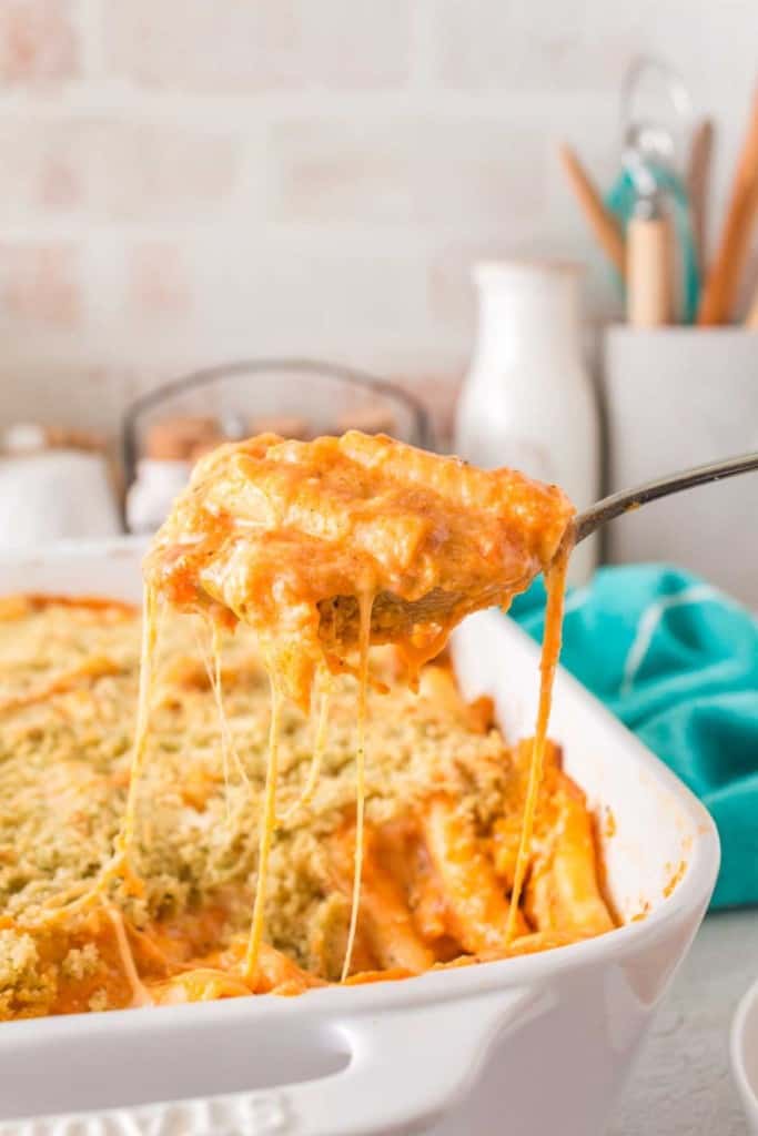five cheese zita forno pasta with a creamy red sauce in a white baking dish being spooned out