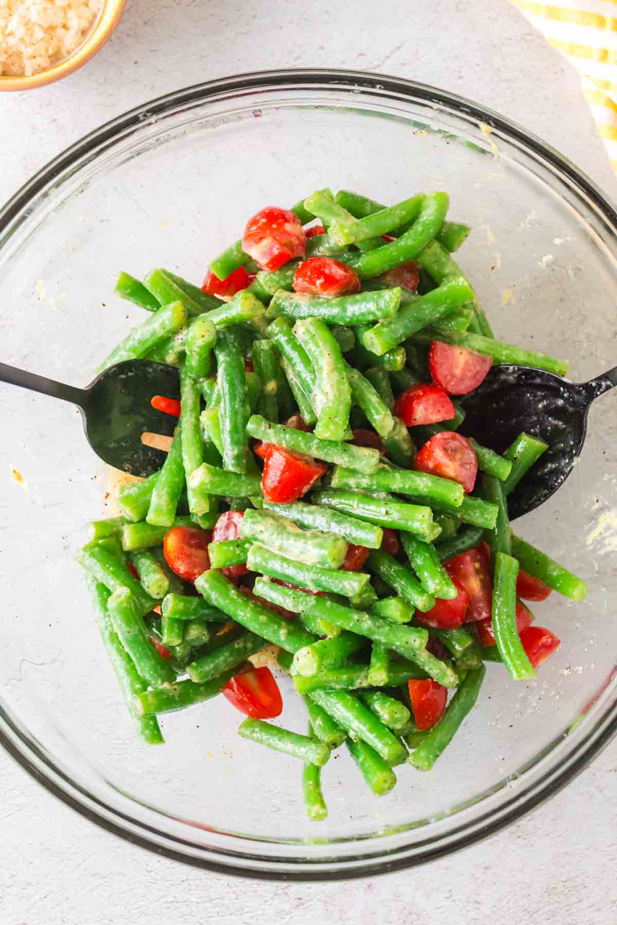 green beans with spices and tomatoes in a clear mixing bowl