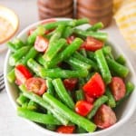 a white bowl of green bean salad with tomatoes