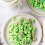 top view of green colored scrambled eggs with pieces of ham on a white plate