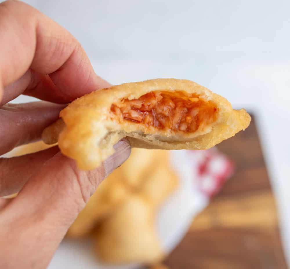 POV hand holding a pizza roll with a bite out