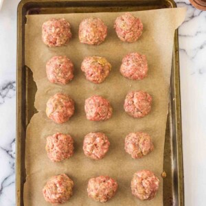 top view of rows of raw Italian meatballs on a parchment lined tray