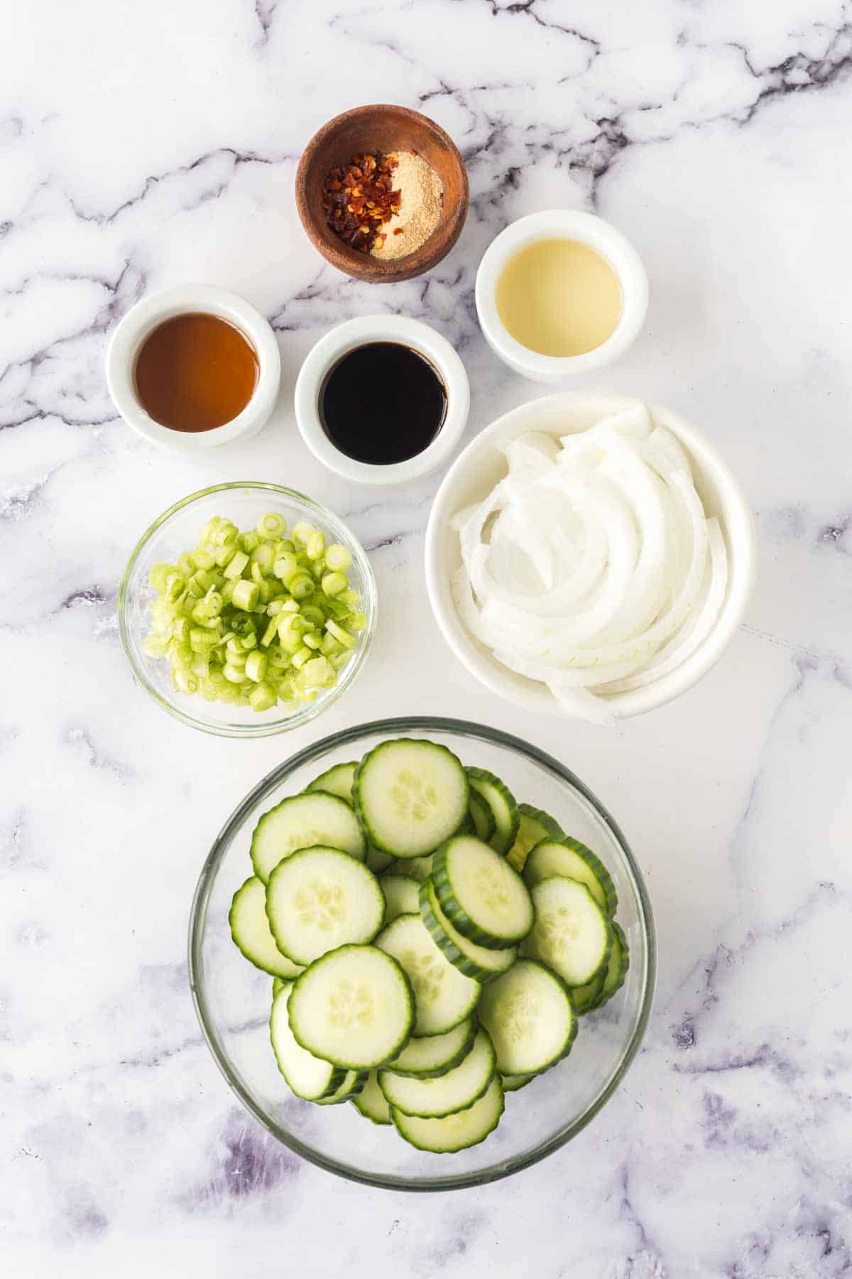 raw ingredients for a korean cucumber salad pre-portioned into small dishes