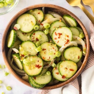 top view of slices of cucumber and spices in a bowl for korean cucumber salad