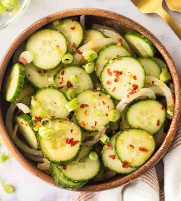 top view of slices of cucumber and spices in a bowl for korean cucumber salad