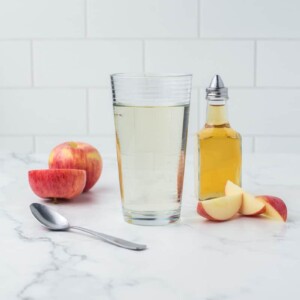 pint glass of apple cider vinegar with sliced apples