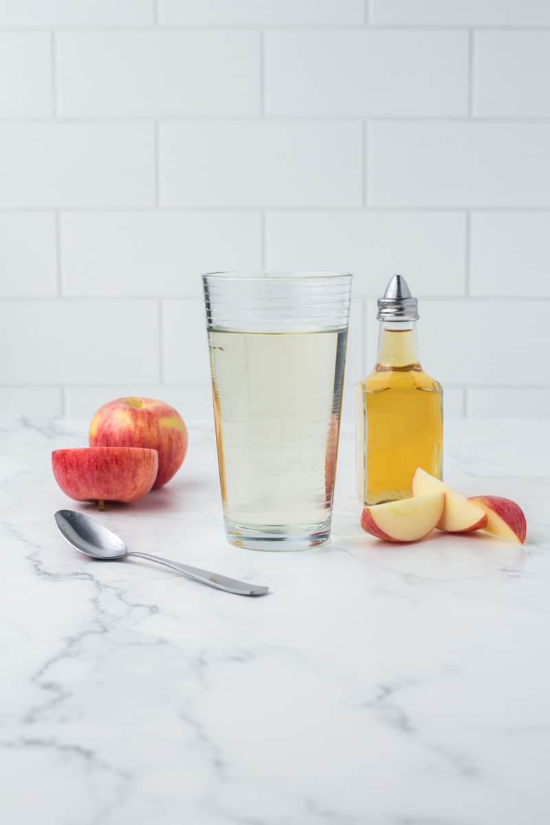 pint glass of apple cider vinegar with sliced apples