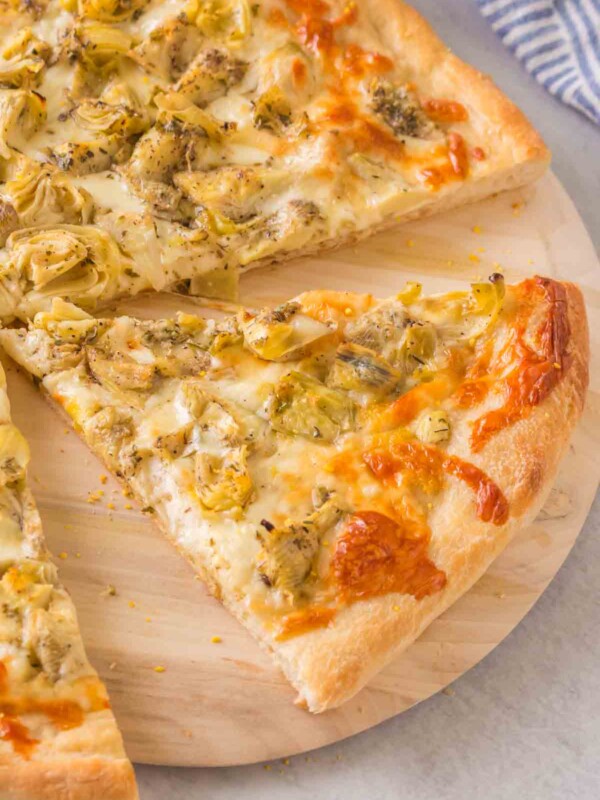 baked artichoke pizza on a wooden paddle
