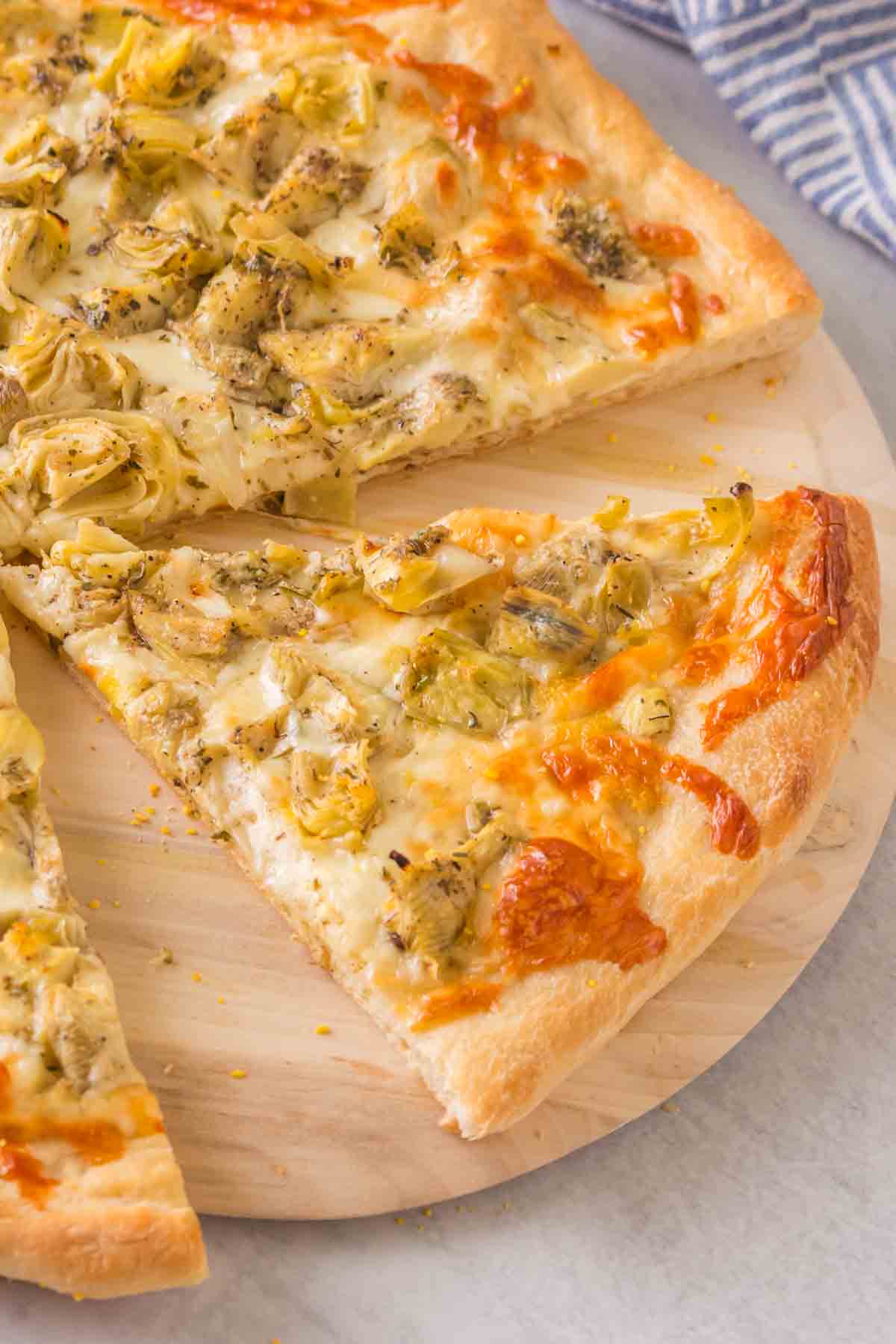baked artichoke pizza on a wooden paddle