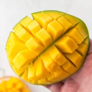 POV hand holding a cube cut mango