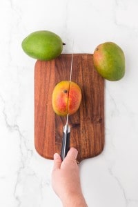 whole fresh mangos on a cutting board