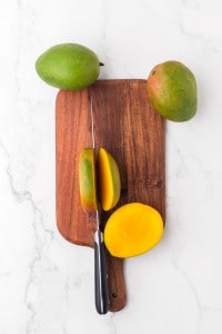 whole mangos on a cutting board