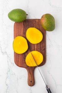 mangoes halved on a cutting board