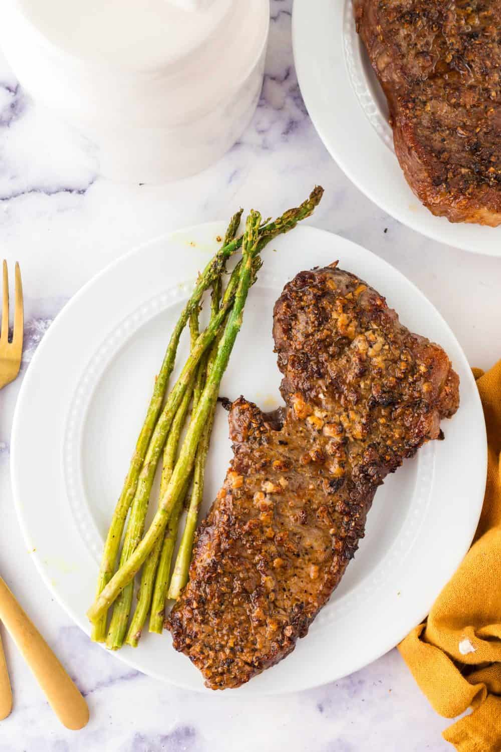 Finished air fryer steak plated next to asparagus.