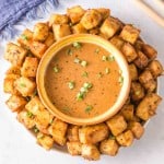 top view of a plate of air fryer tofu with a dish of dipping sauce in the center.