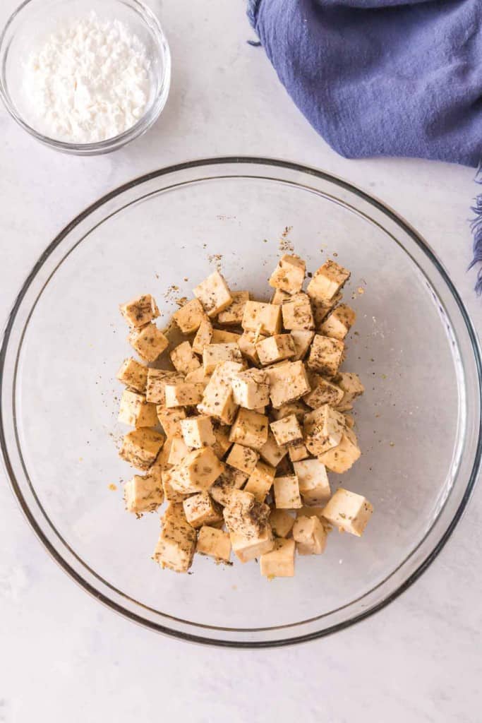 seasoned cubes of tofu in a clear glass bowl