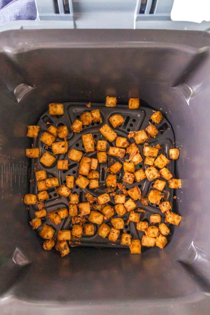 cubes of seasoned tofu in an air fryer basket