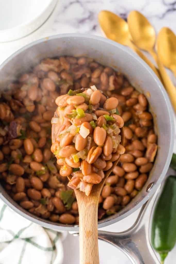 Spoonful of charro beans over a pot.