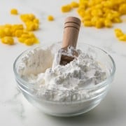 Cornstarch in a bowl with water to make a slurry and corn kernels all around
