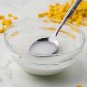 corn starch slurry bowl with a bottle of corn starch and corn kernels all around