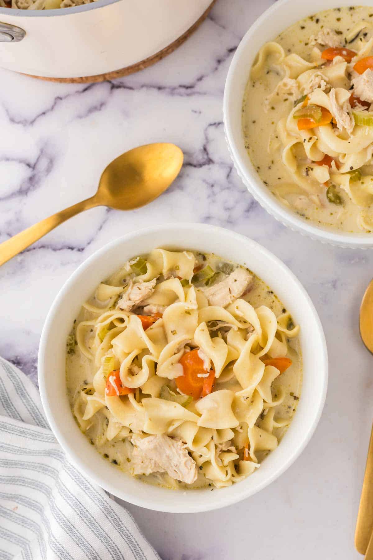 top view of a white bowl of creamy chicken noodle soup