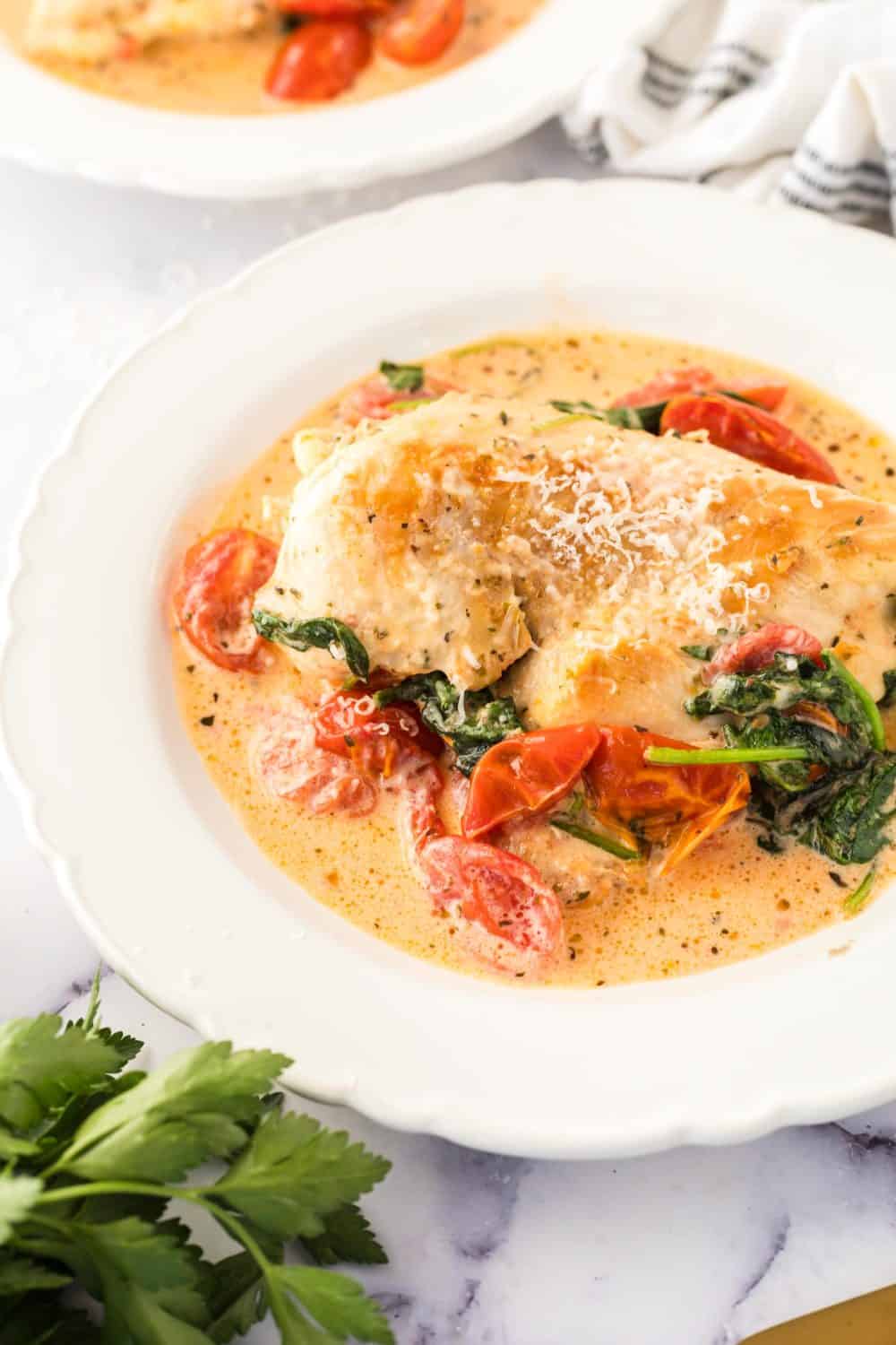 Creamy tuscan chicken in a white bowl. 