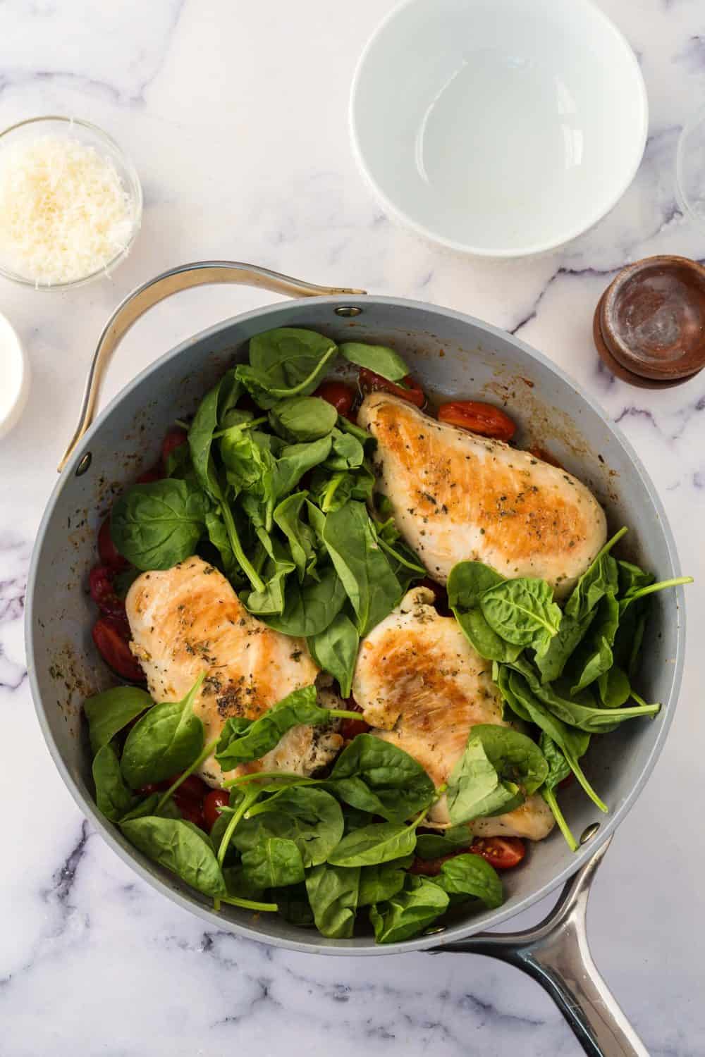 Ingredients in a pot preparing to cook creamy tuscan chicken.